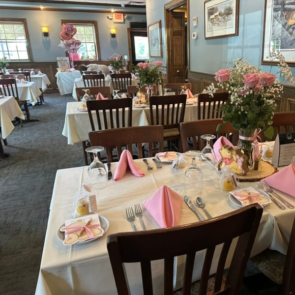 Restaurant dining room set for a baby shower with pink decorations, balloons, and Winnie the Pooh cookies.